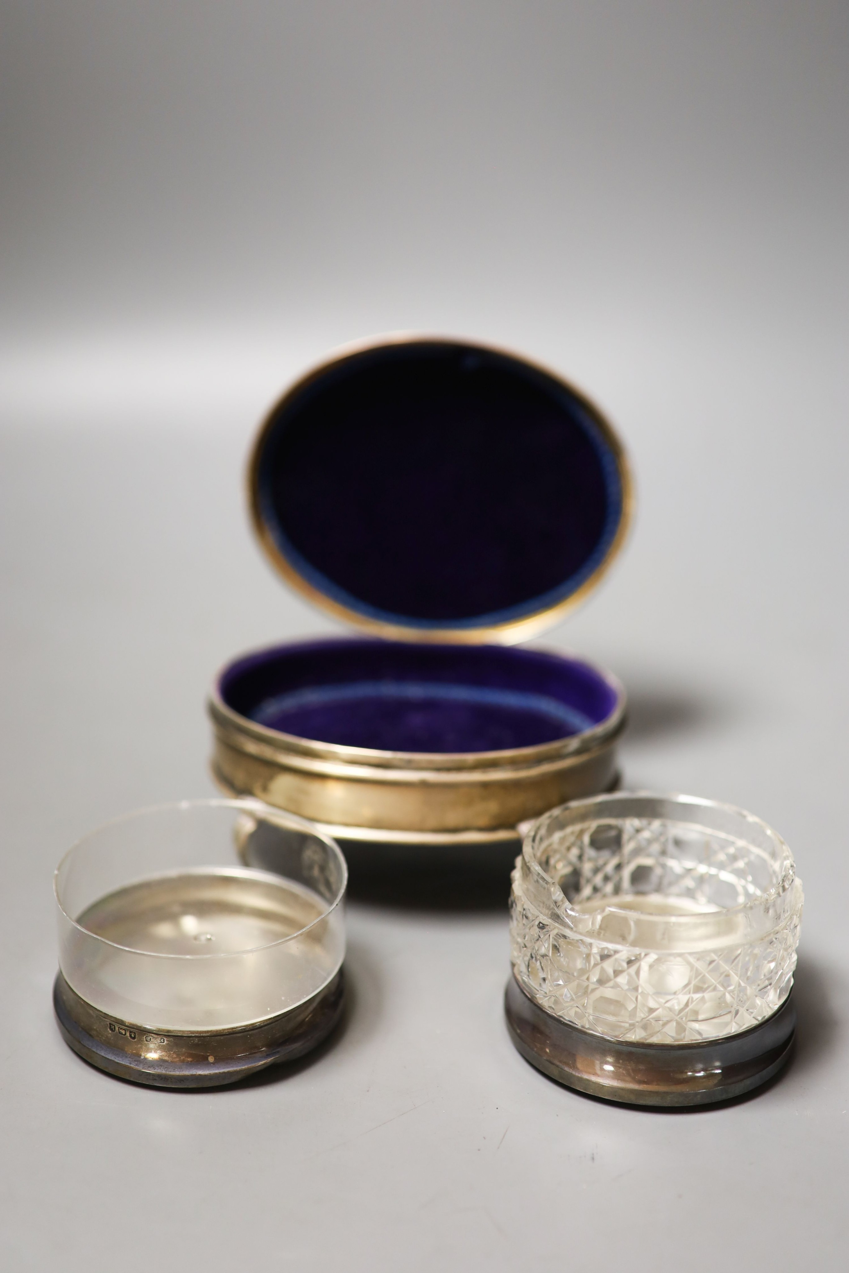 An Edwardian silver oval trinket box, William Comyns, London, 1909, 12.4cm and two round silver mounted glass toilet boxes.